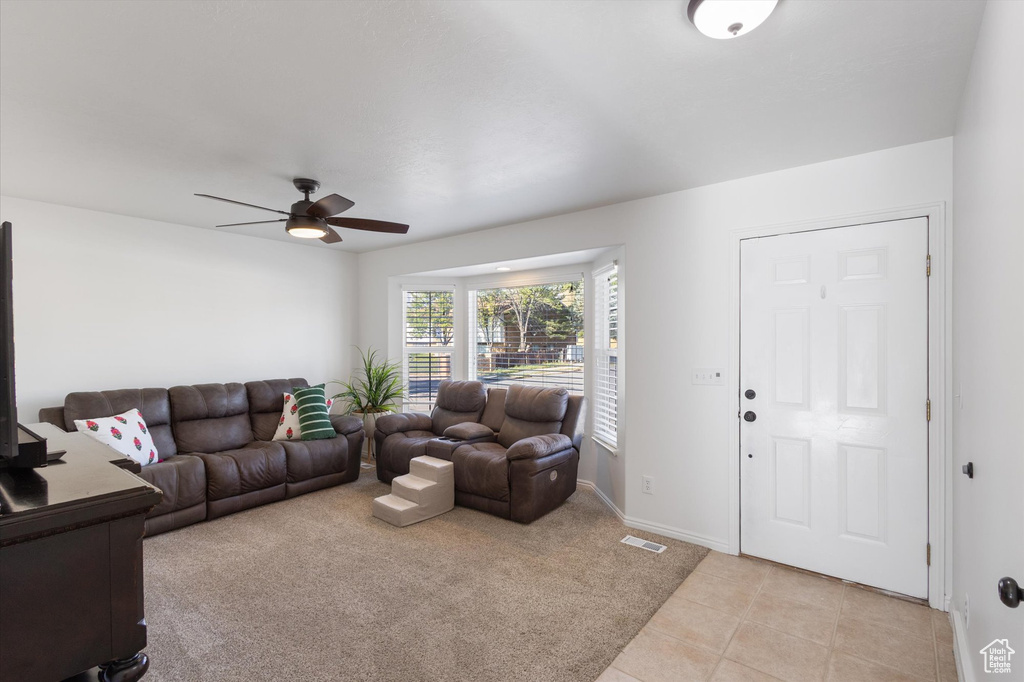 Living room with light tile patterned flooring, light carpet, a ceiling fan, baseboards, and visible vents