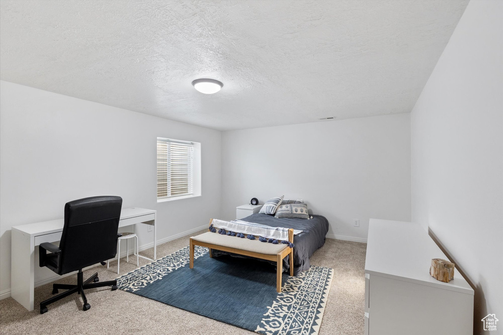 Bedroom with carpet flooring, a textured ceiling, and baseboards