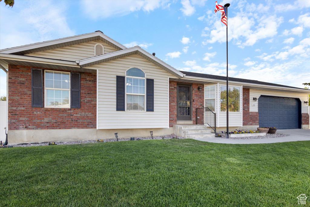 Single story home with an attached garage, a front lawn, and brick siding
