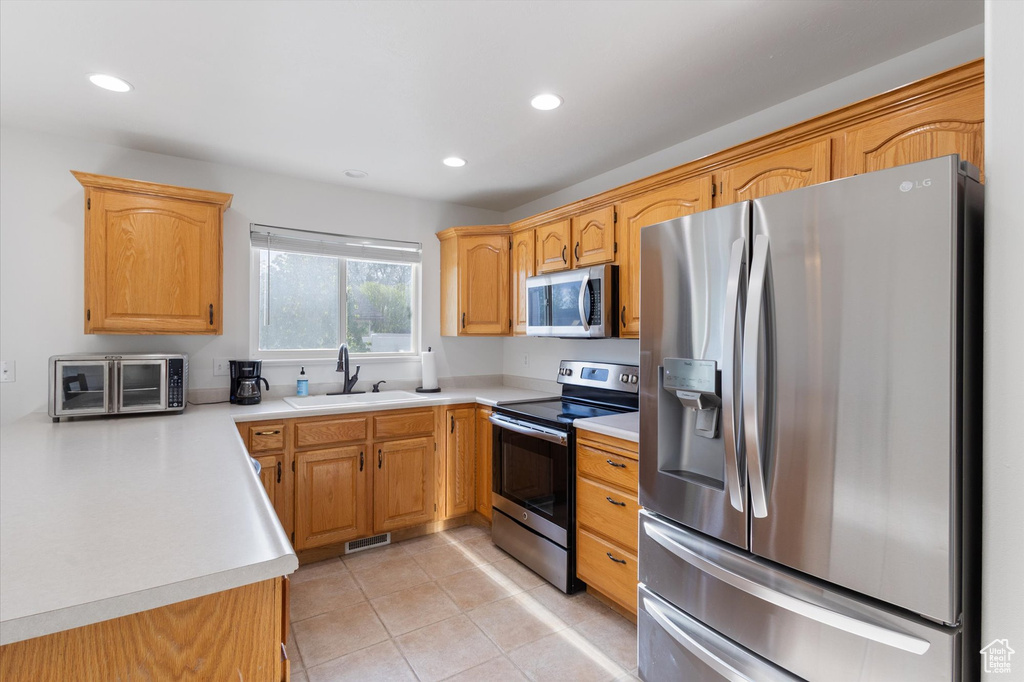 Kitchen featuring light countertops, stainless steel appliances, recessed lighting, and a sink