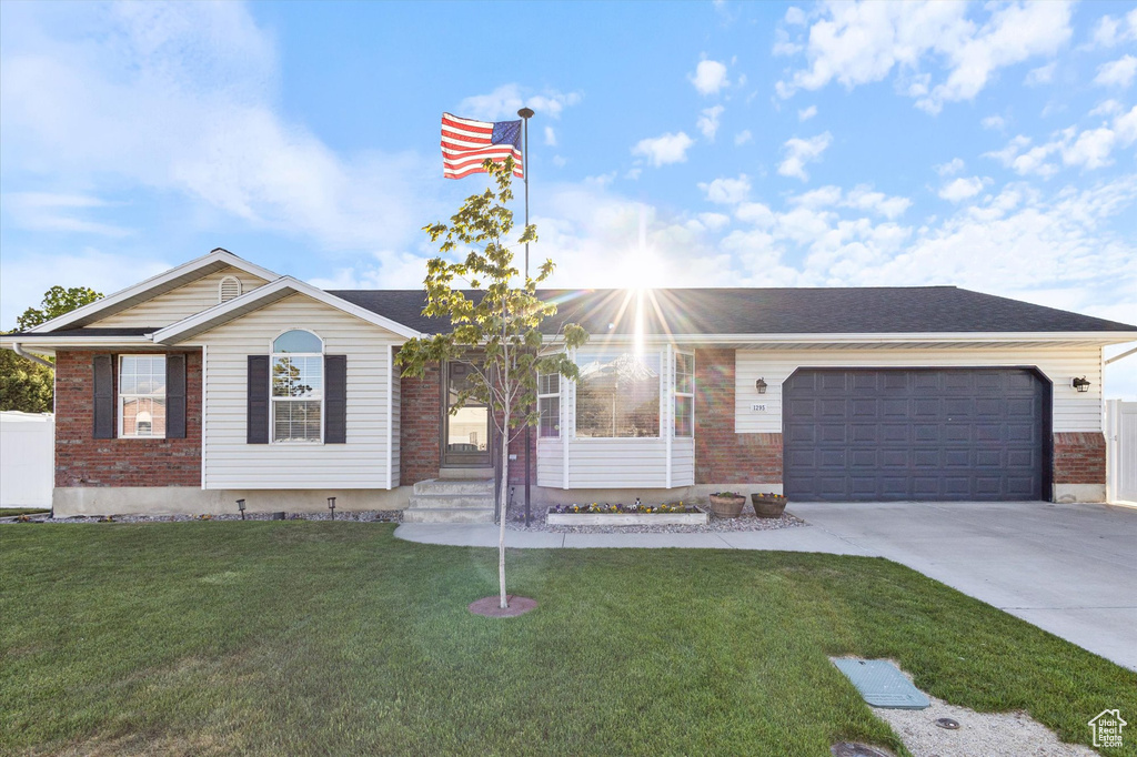 Ranch-style house with concrete driveway, brick siding, an attached garage, and a front lawn