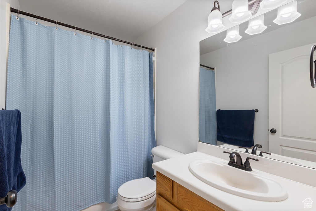 Bathroom with vanity, a shower with curtain, and toilet