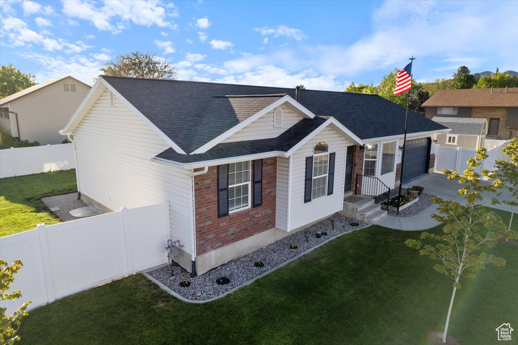 View of front of house with a garage, brick siding, roof with shingles, and a front yard