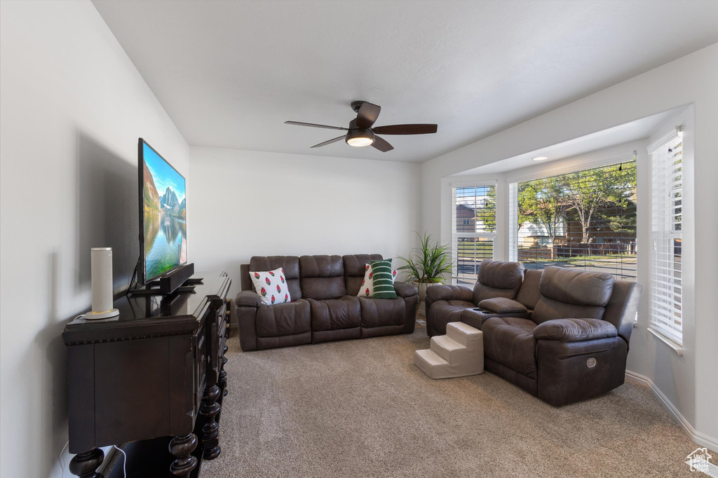 Carpeted living area featuring visible vents, a ceiling fan, and baseboards