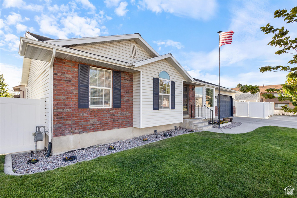 Ranch-style home with a front yard, a garage, brick siding, fence, and concrete driveway