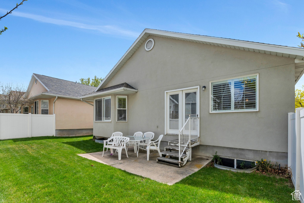 Rear view of house featuring a patio area, fence, a yard, and stucco siding