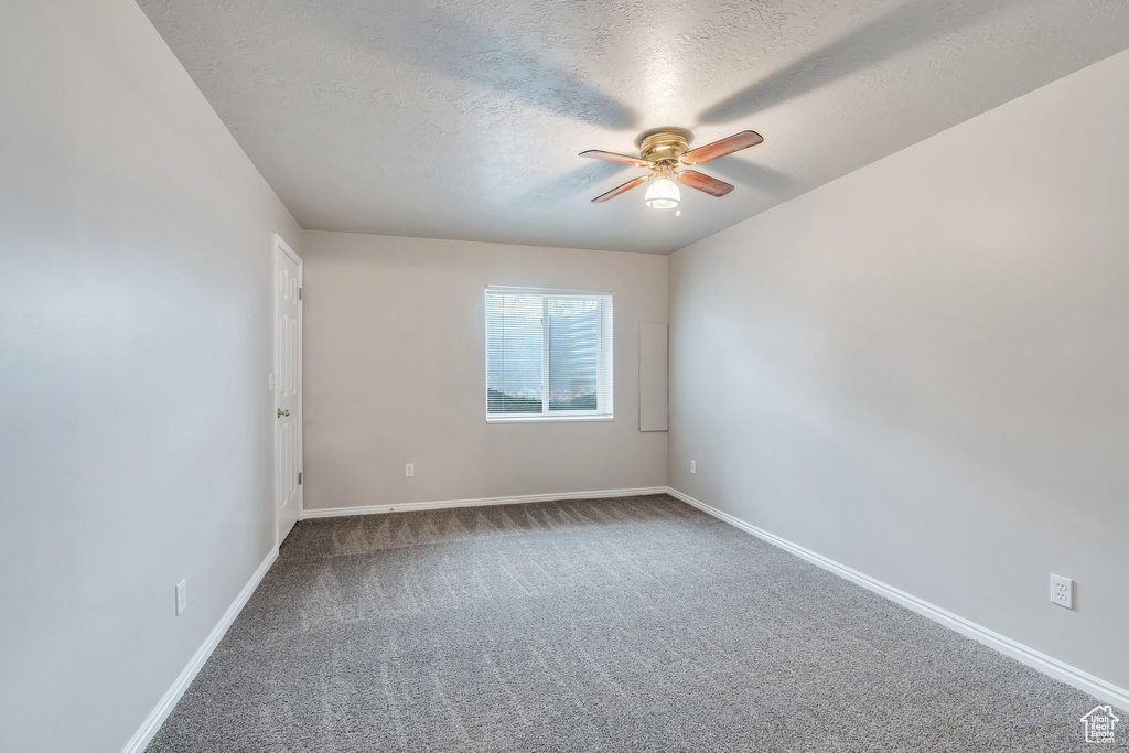 Carpeted empty room with baseboards, a ceiling fan, and a textured ceiling