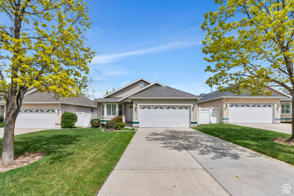 Ranch-style home with fence, concrete driveway, a front lawn, and stucco siding