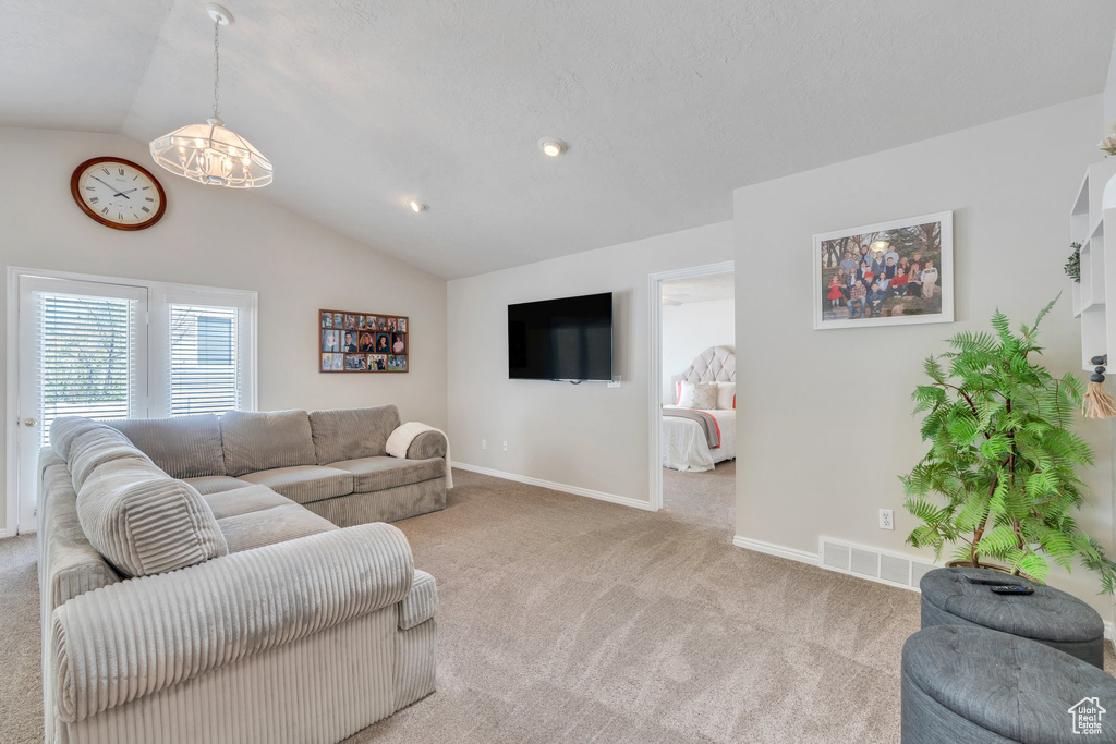 Living area featuring baseboards, vaulted ceiling, visible vents, and carpet