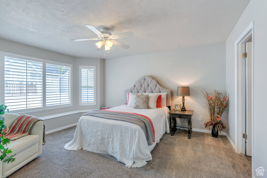Carpeted bedroom featuring a textured ceiling, baseboards, and ceiling fan