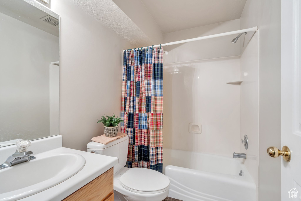 Bathroom featuring toilet, vanity, shower / tub combo with curtain, and visible vents