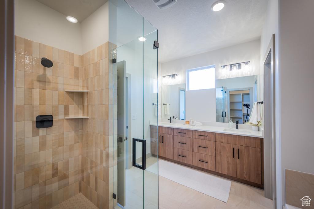 Bathroom with double vanity, tile patterned floors, a shower stall, and a sink
