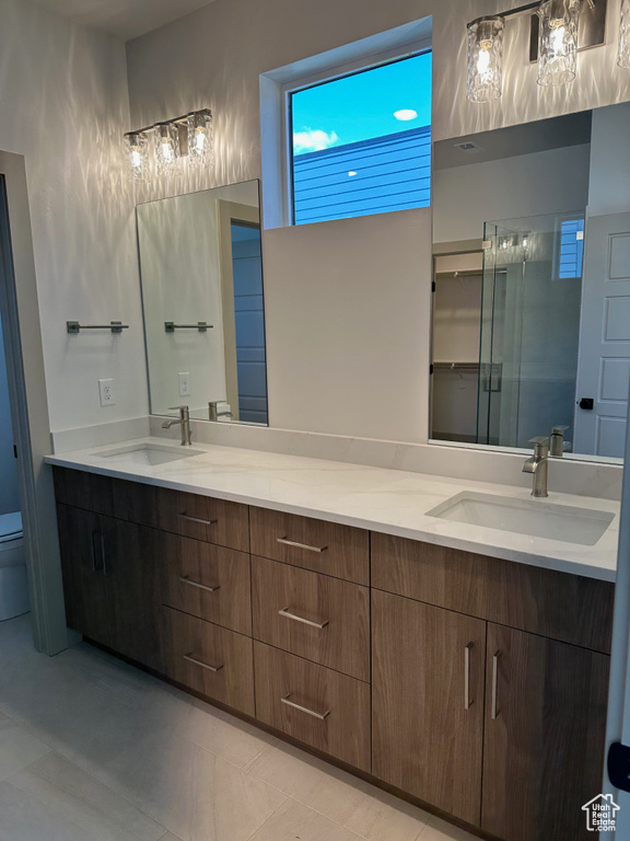 Full bath with double vanity, a sink, toilet, and a shower stall