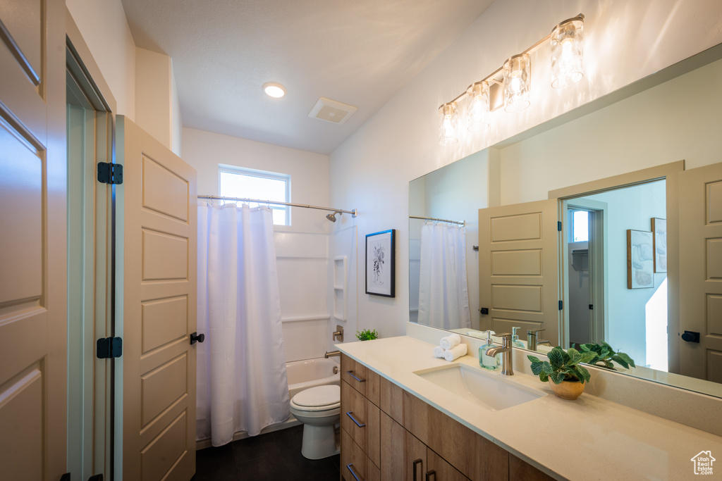 Full bathroom featuring vanity, shower / bath combo with shower curtain, and toilet