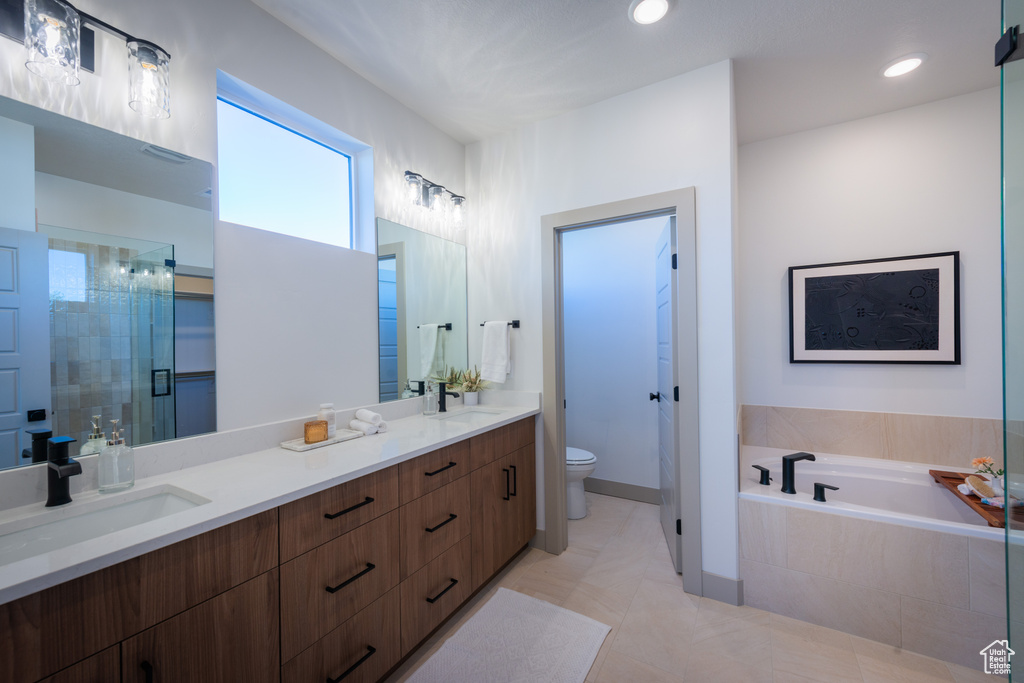 Full bath featuring toilet, a sink, a bath, and a stall shower