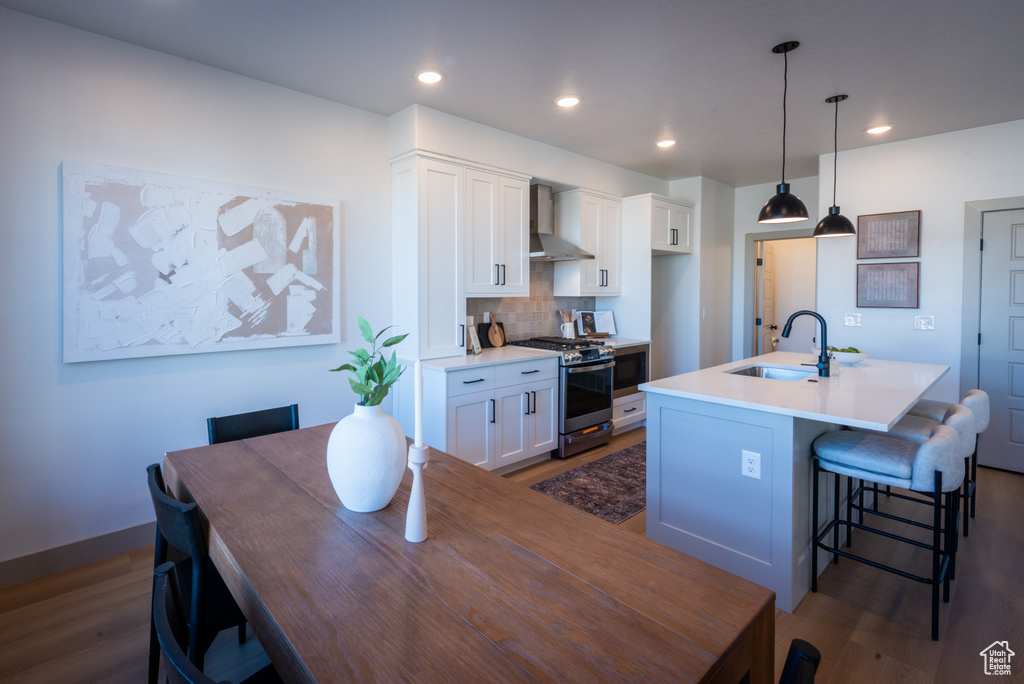 Kitchen featuring a sink, wall chimney exhaust hood, appliances with stainless steel finishes, and dark wood finished floors
