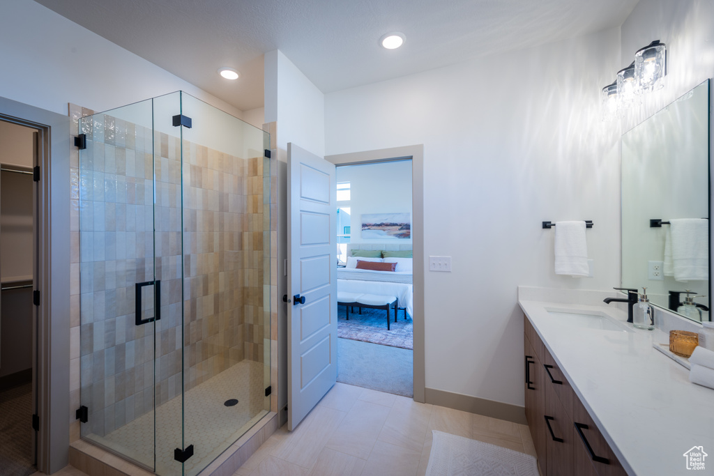 Bathroom featuring connected bathroom, vanity, recessed lighting, baseboards, and a stall shower