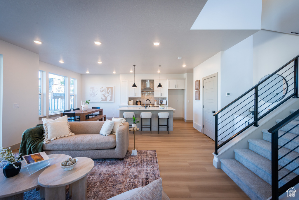 Living area with recessed lighting, light wood-style flooring, baseboards, and stairway