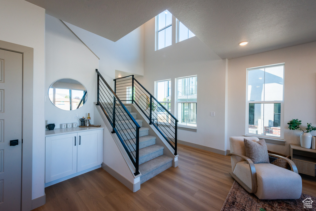 Staircase with baseboards, a high ceiling, radiator, and wood finished floors