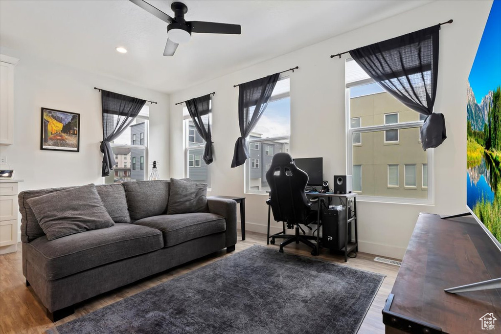 Office area with baseboards, a ceiling fan, light wood finished floors, and visible vents