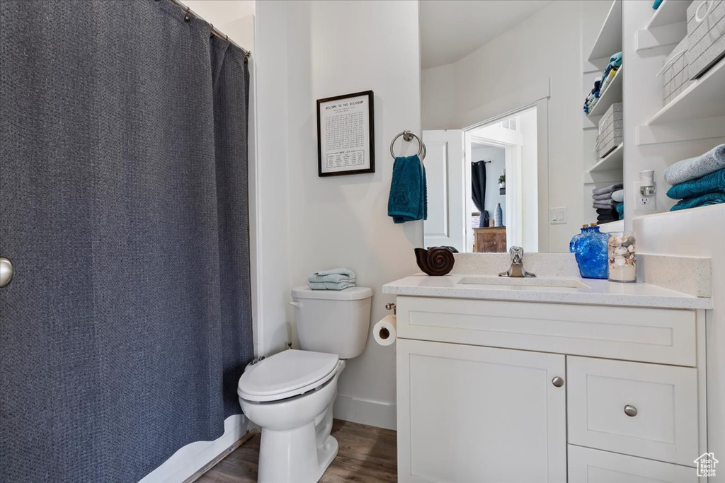 Full bath with a shower with shower curtain, toilet, wood finished floors, and vanity