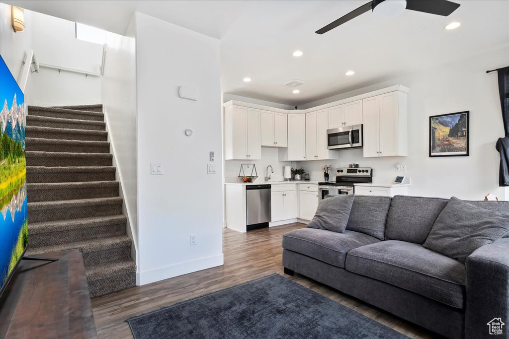 Living area featuring dark wood-style flooring, ceiling fan, stairs, recessed lighting, and baseboards