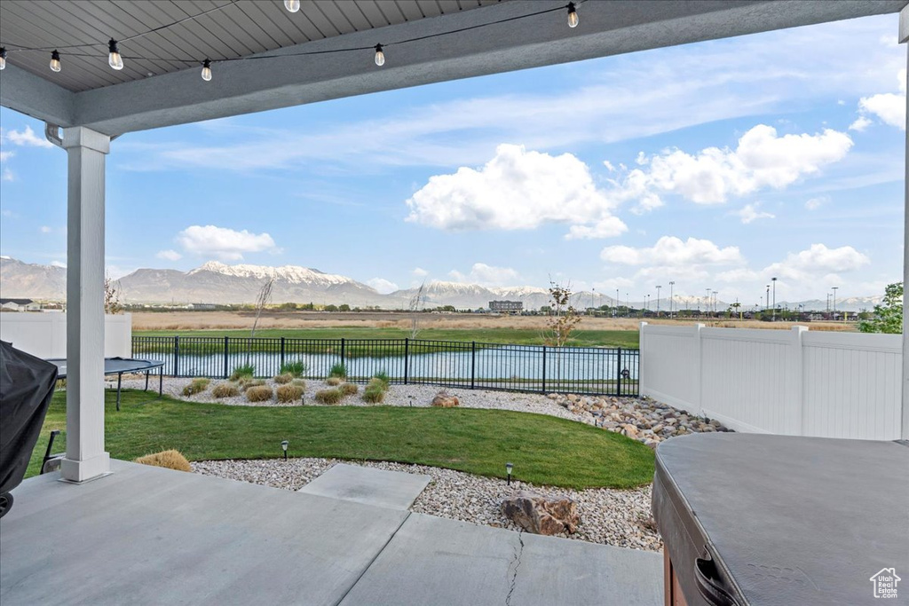 View of patio / terrace with a fenced backyard, a trampoline, and a water and mountain view