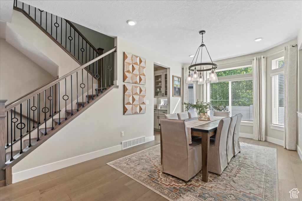 Dining room with visible vents, wood finished floors, stairway, baseboards, and a chandelier