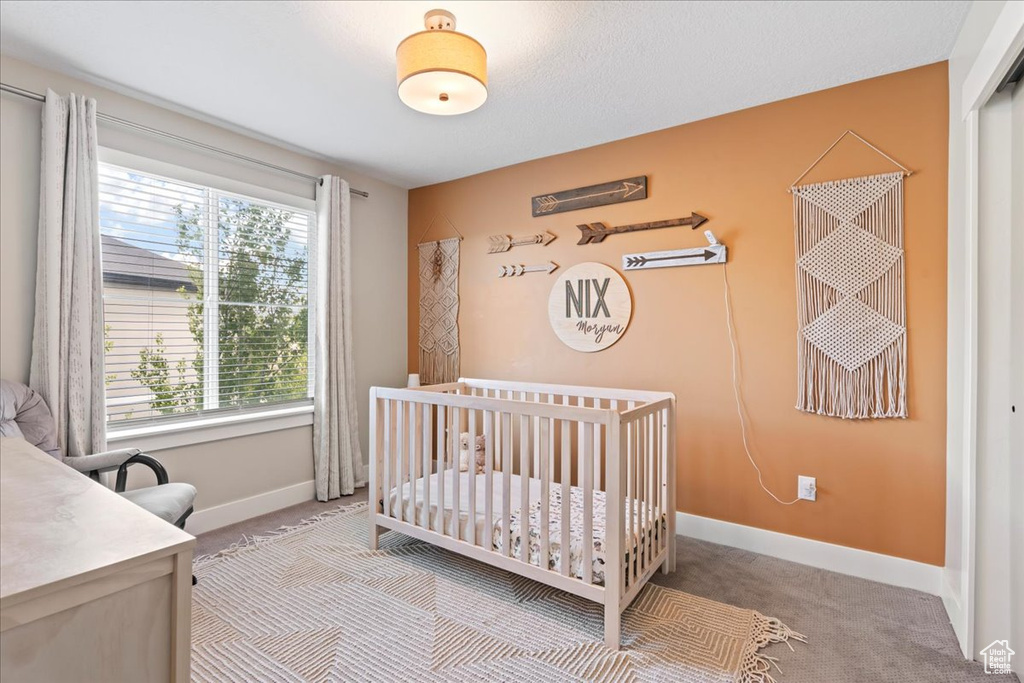 Bedroom with baseboards, carpet flooring, and a crib