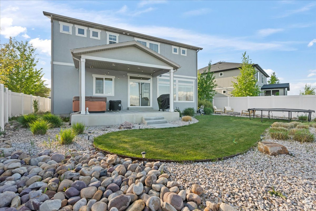 Back of house featuring stucco siding, a fenced backyard, a hot tub, and a patio area