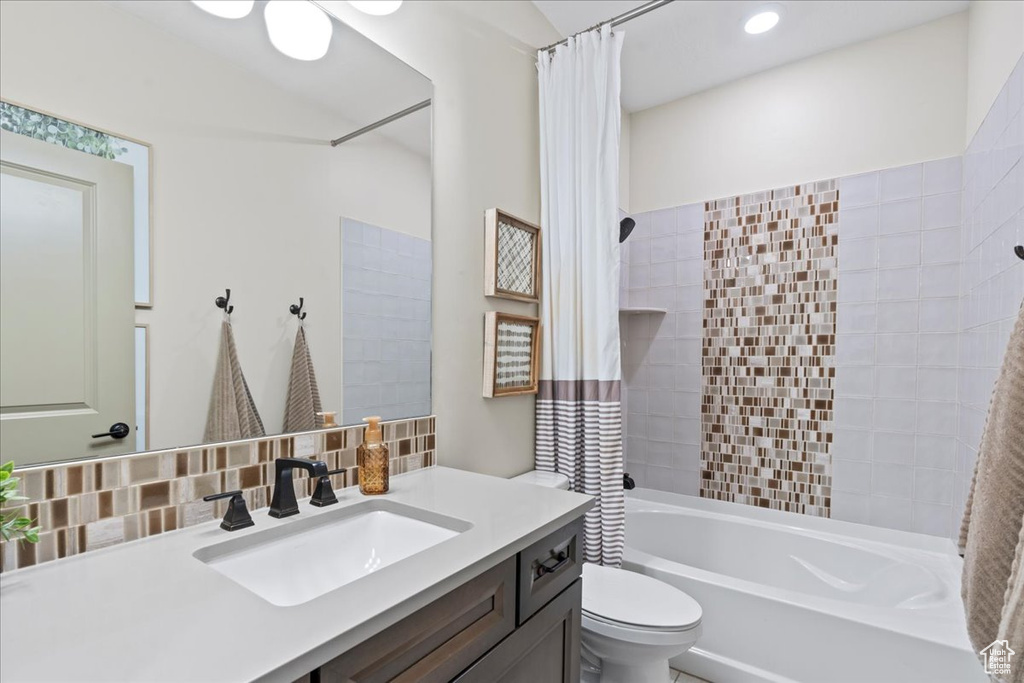 Bathroom with vanity, tasteful backsplash, toilet, and shower / bath combination with curtain