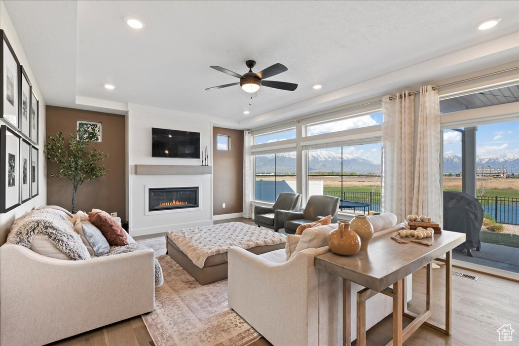 Living area featuring light wood-style floors, plenty of natural light, ceiling fan, and a large fireplace