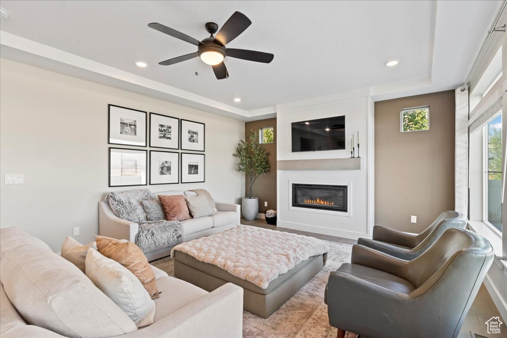 Living area featuring recessed lighting, ceiling fan, a large fireplace, and a raised ceiling