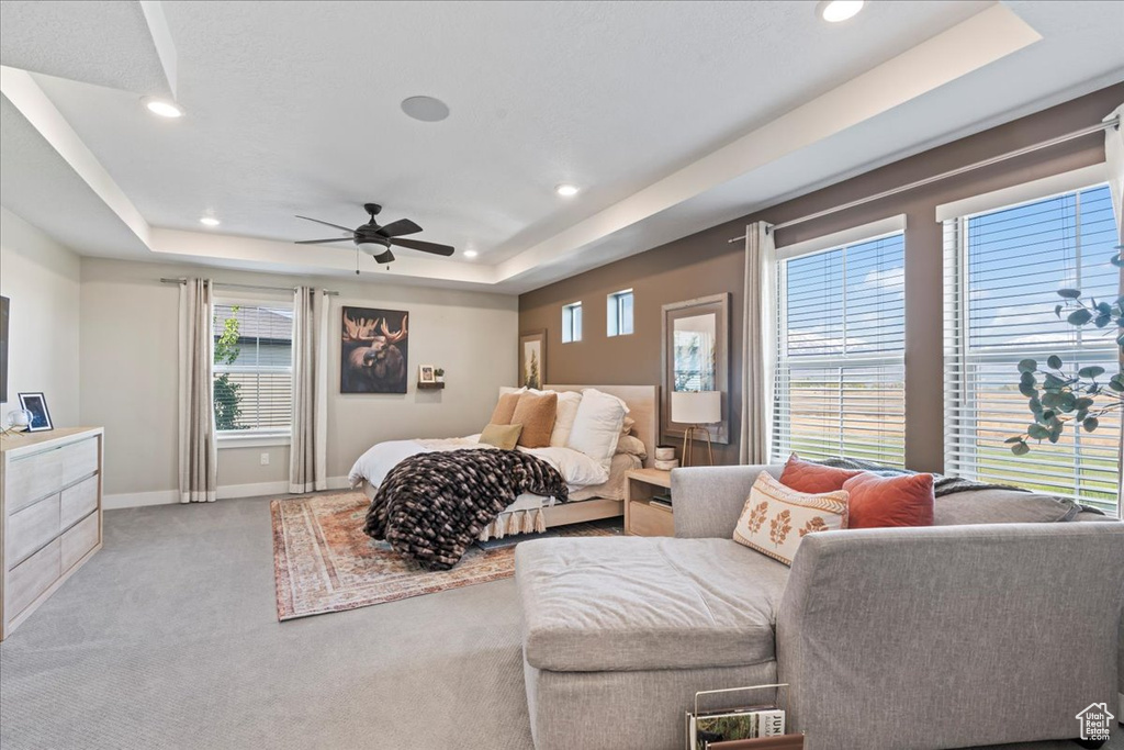 Carpeted bedroom featuring a raised ceiling, multiple windows, and recessed lighting