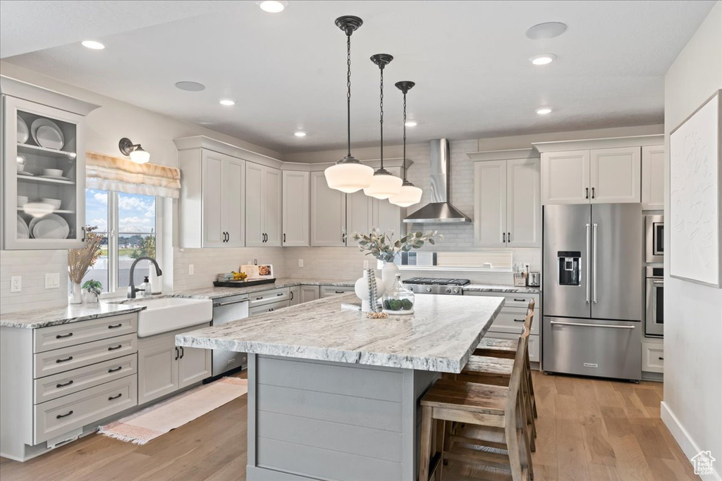 Kitchen with a sink, wall chimney exhaust hood, appliances with stainless steel finishes, and tasteful backsplash