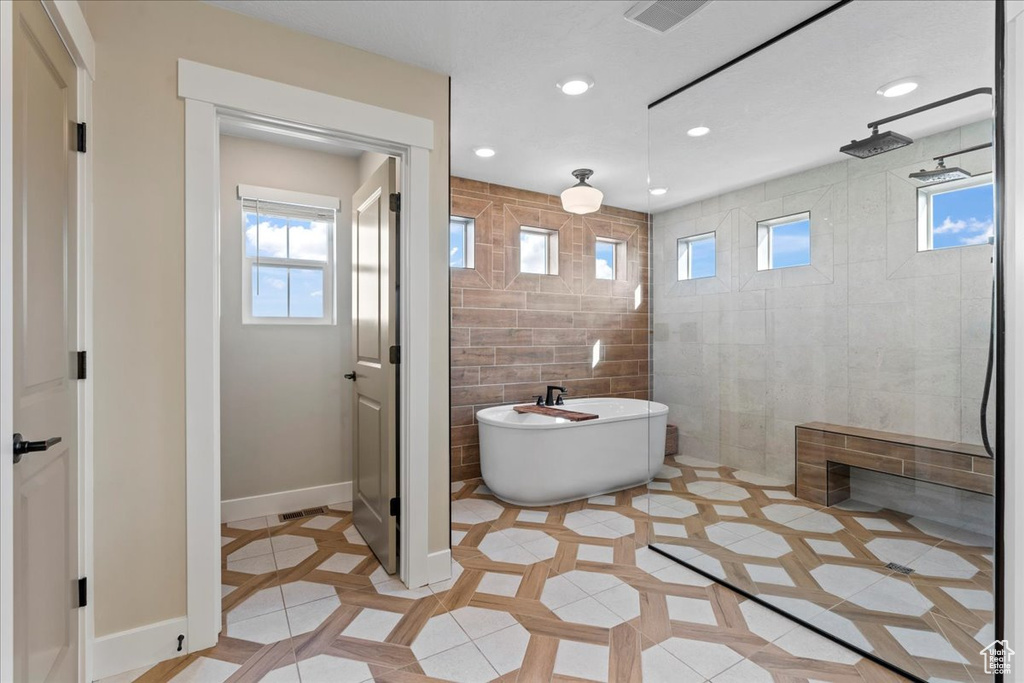 Full bathroom featuring a freestanding bath, tile patterned floors, walk in shower, and a wealth of natural light