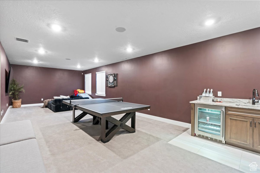 Recreation room with beverage cooler, wet bar, visible vents, and light carpet