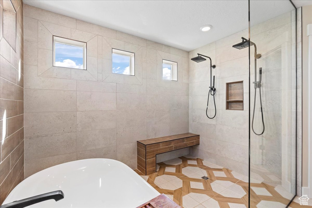 Bathroom with tile patterned flooring, a freestanding tub, and a tile shower