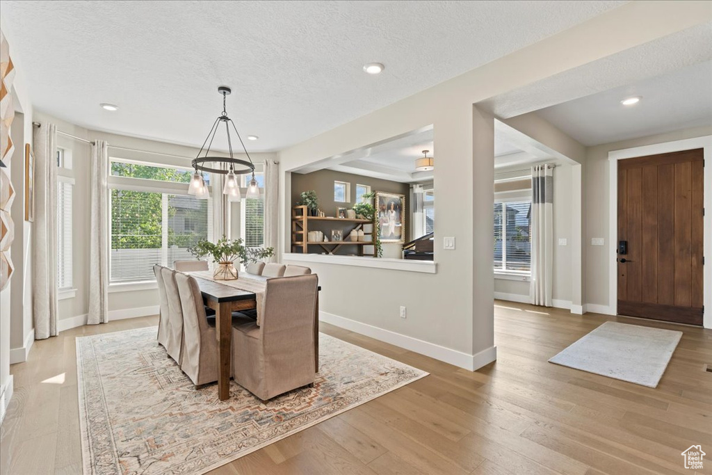Dining area with a notable chandelier, a textured ceiling, recessed lighting, baseboards, and wood finished floors