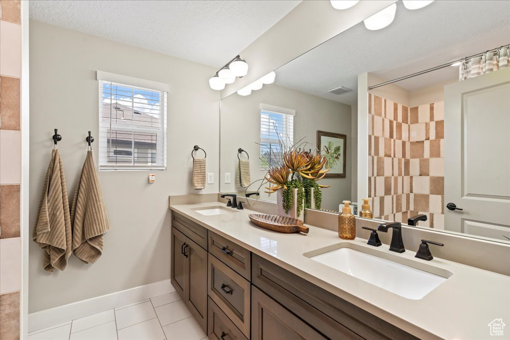 Bathroom featuring baseboards, a sink, tile patterned flooring, and double vanity