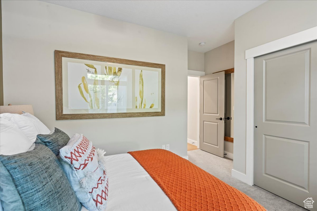 Bedroom featuring baseboards, light colored carpet, and a closet