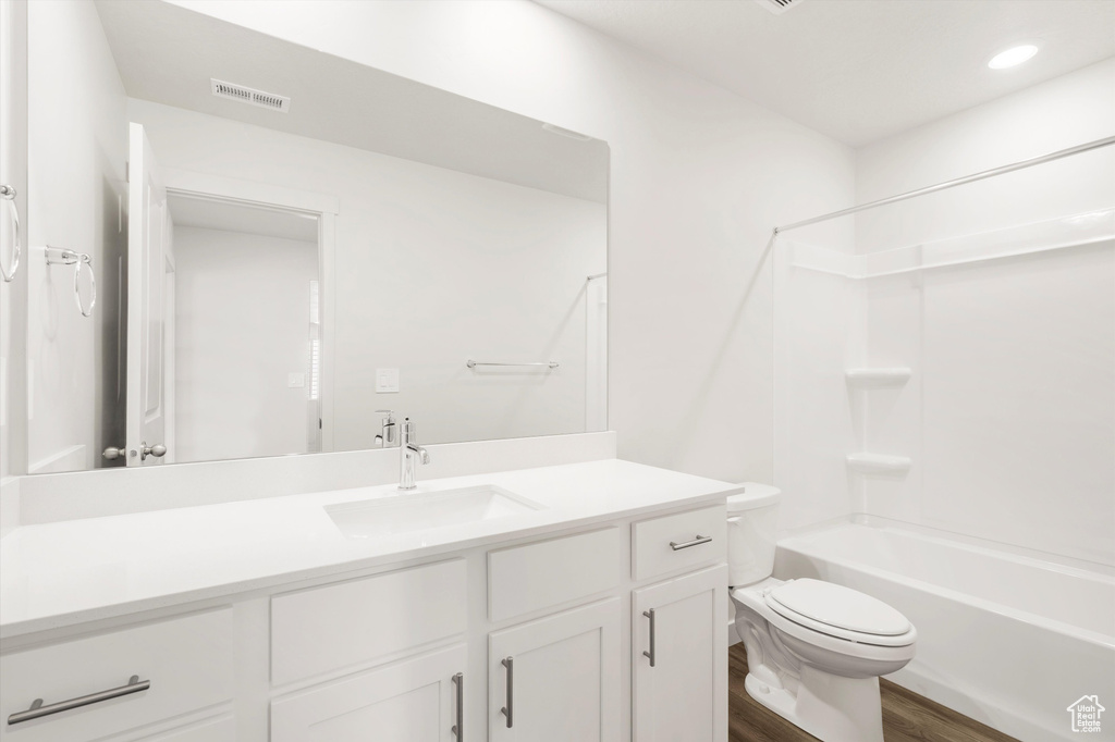 Full bath with vanity, toilet, wood finished floors, and shower / washtub combination