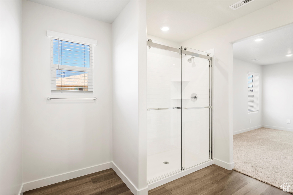 Full bathroom featuring a stall shower, wood finished floors, healthy amount of natural light, and recessed lighting