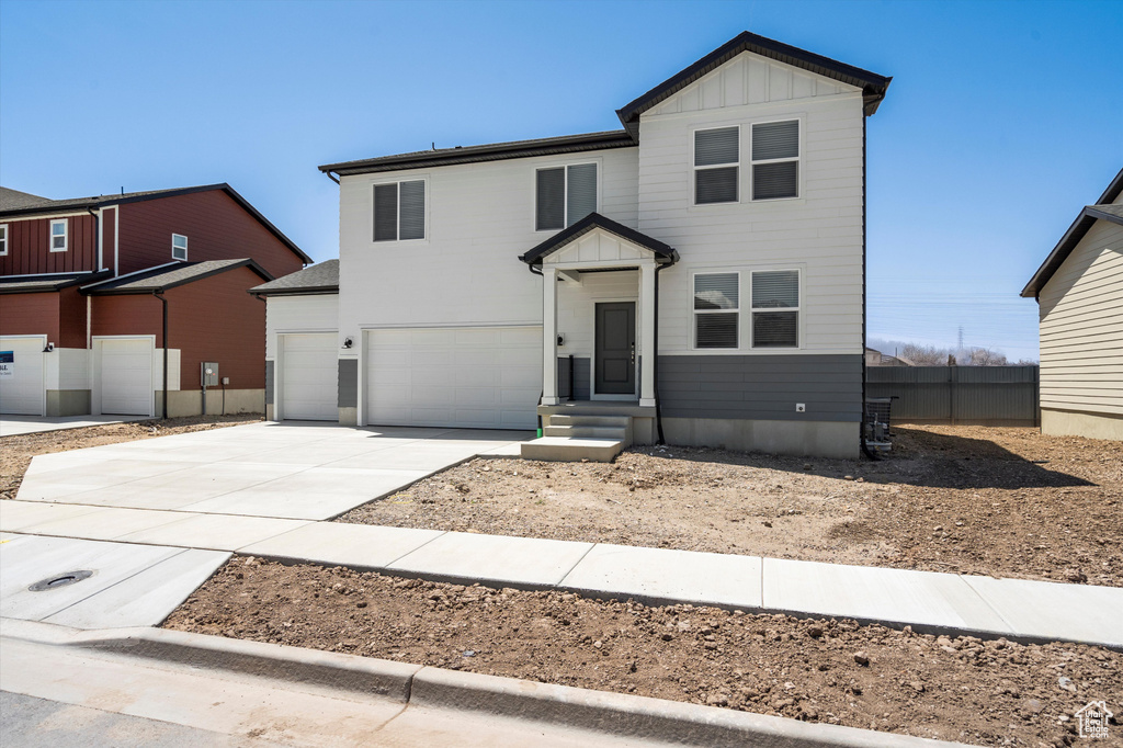 View of front of house with board and batten siding, concrete driveway, and a garage
