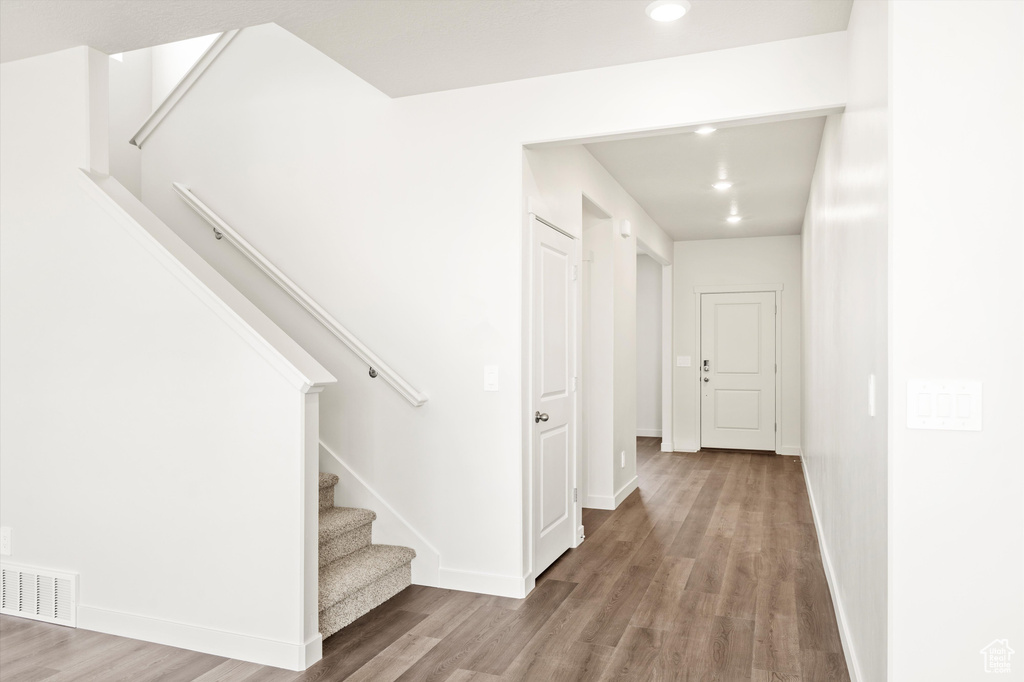 Hall featuring wood finished floors, stairway, baseboards, and recessed lighting