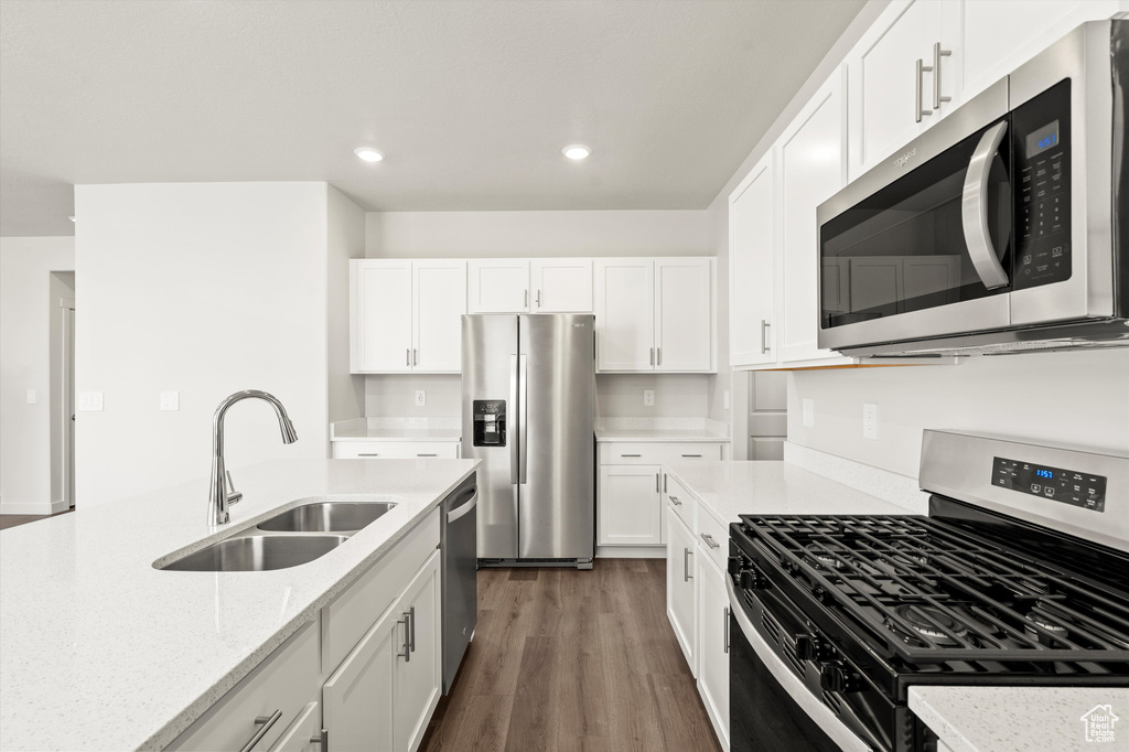 Kitchen featuring appliances with stainless steel finishes, a sink, dark wood-style flooring, white cabinetry, and recessed lighting