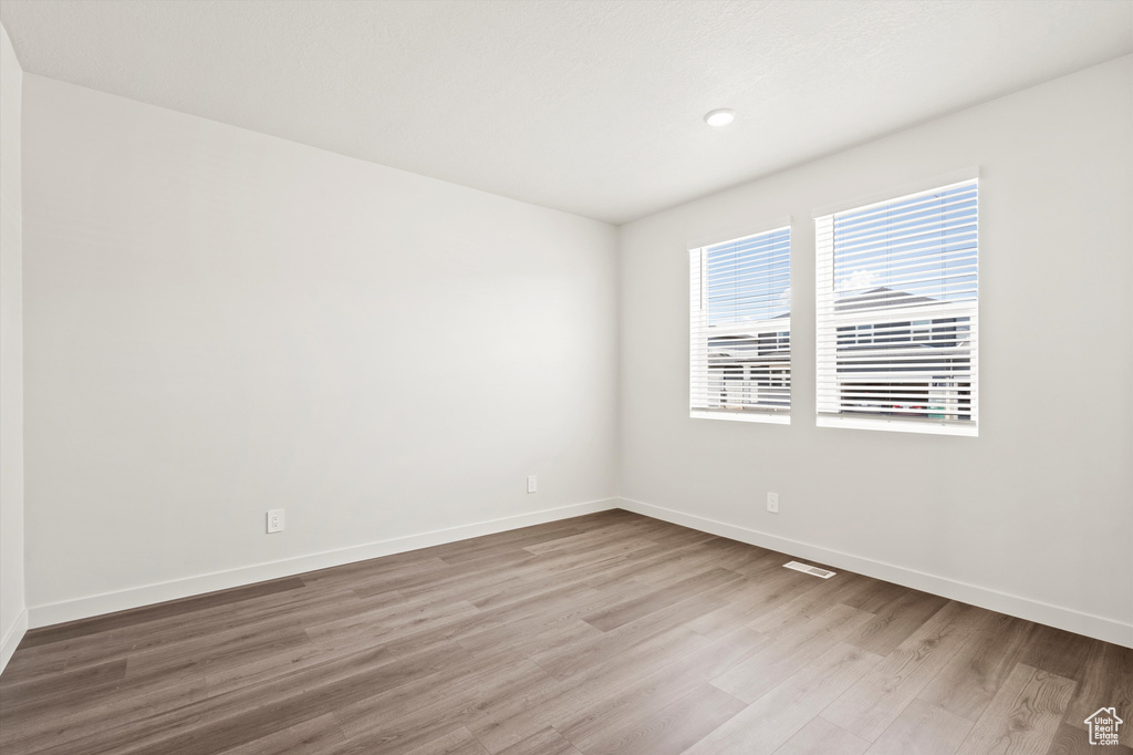 Empty room featuring wood finished floors, baseboards, and recessed lighting