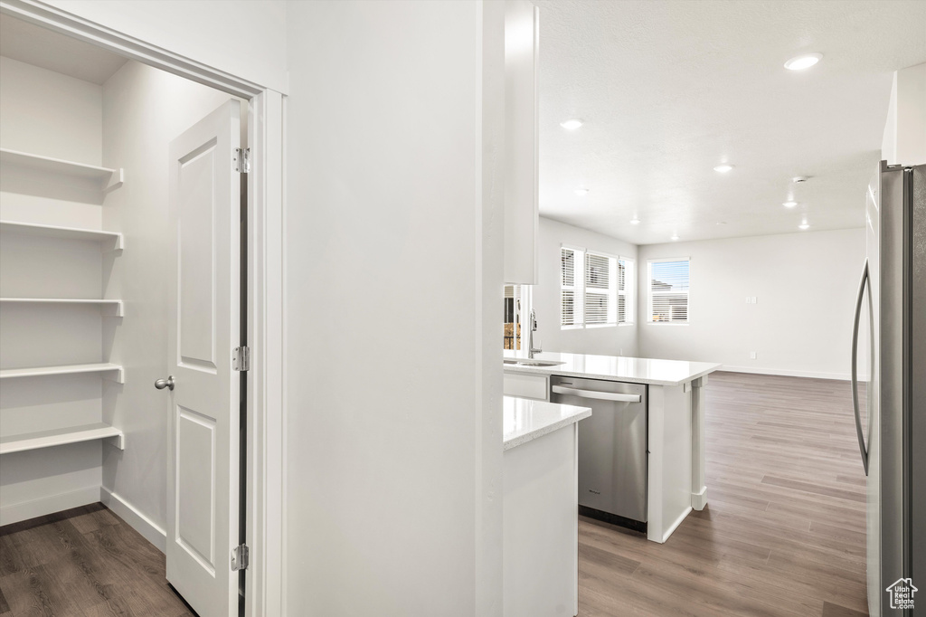 Kitchen featuring stainless steel appliances, wood finished floors, light countertops, recessed lighting, and a peninsula