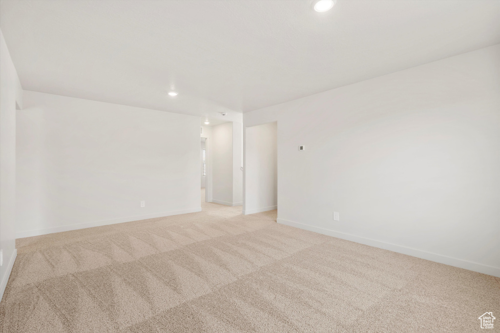 Empty room with light carpet, recessed lighting, and baseboards