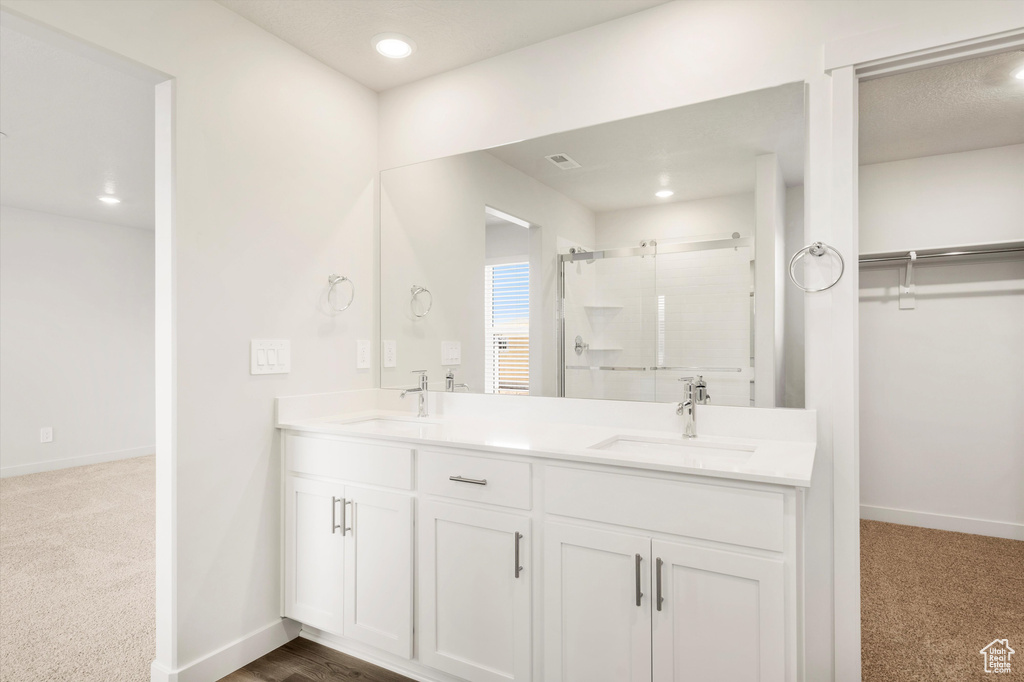 Full bath with a shower stall, baseboards, double vanity, recessed lighting, and a spacious closet